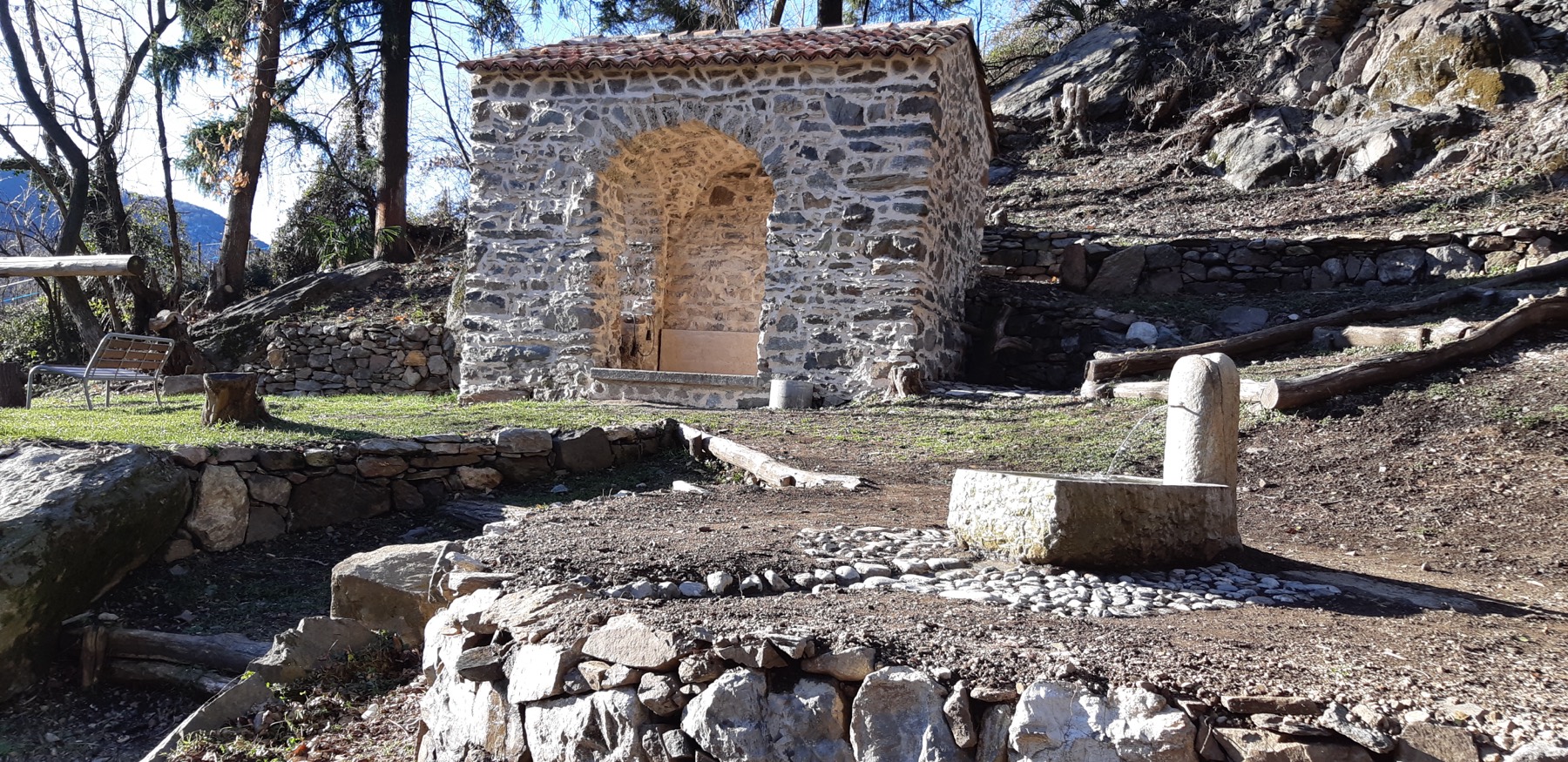 La cappella di San Rocco restaurata, con le mura in pietra e il nuovo tetto, immersa nel bosco alle porte di Rovio
